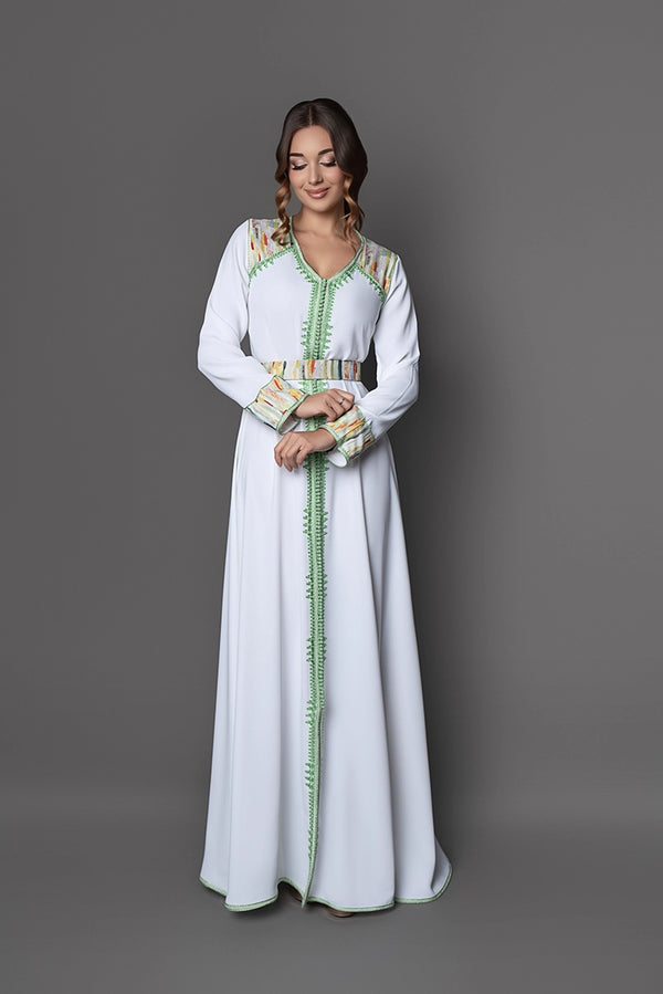 Femme portant le caftan marocain Pipa blanc et vert, coupe fluide et ceinture coordonnée, création raffinée pour mariage et occasion spéciale.